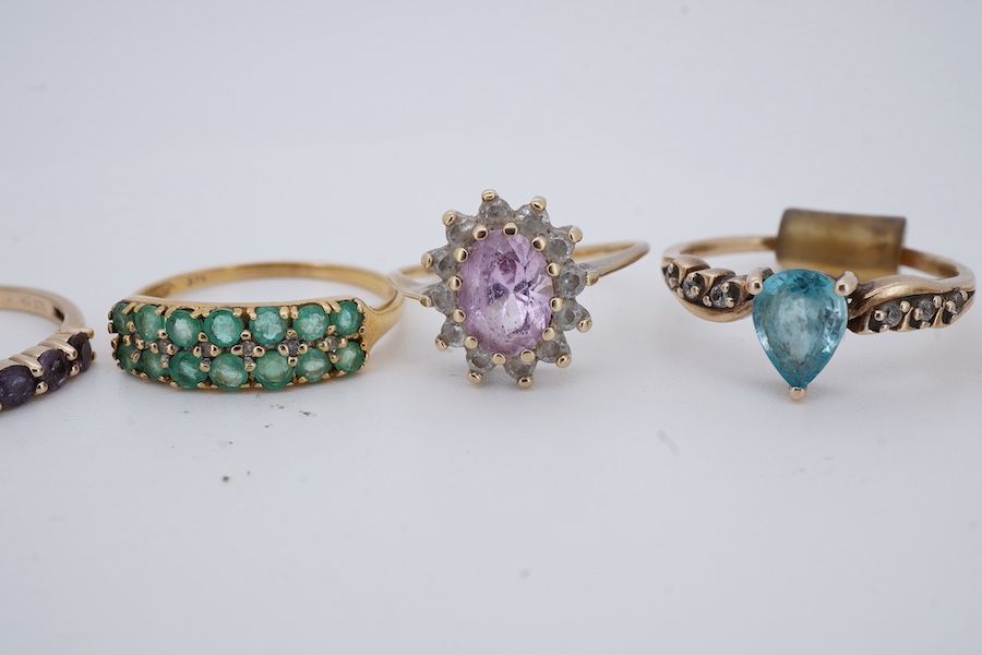 Seven gem-set rings, comprising: a faceted opal and diamond ring; a kunzite and colourless paste cluster ring; a garnet cluster ring; a blue zircon and colourless paste ring; and a tanzanite ring, all mounted in 9ct gold